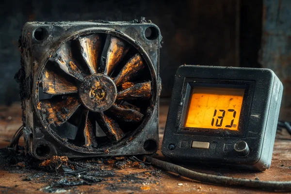 a burnt-out fan motor next to a voltmeter showing an incorrect voltage