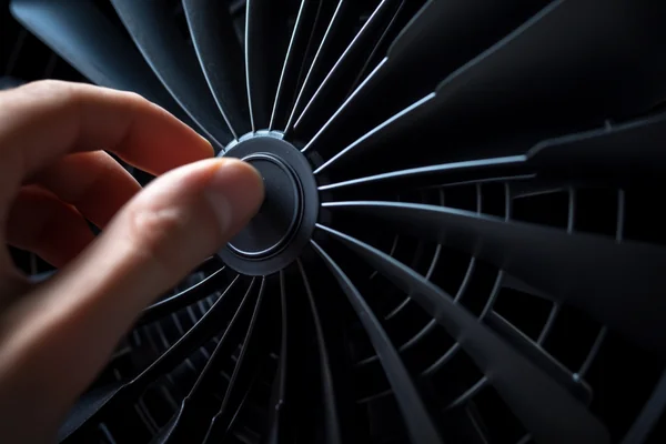 A person's hand gently spinning a DC fan blade to check its movement.