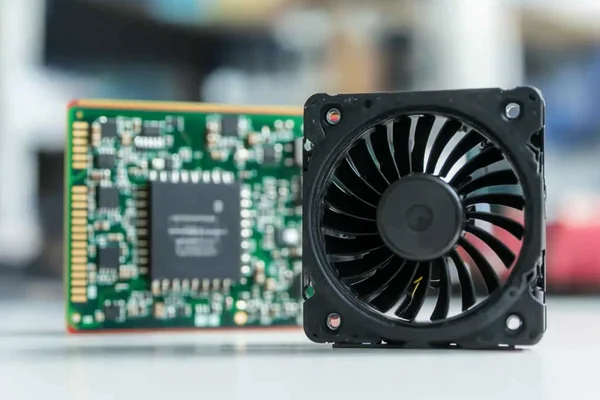 A small 5V DC axial fan placed next to a Raspberry Pi to show its common application and scale
