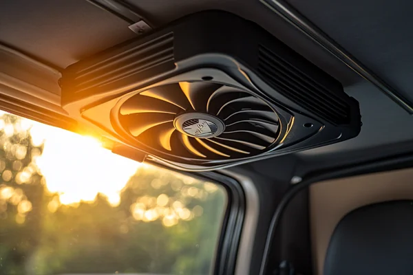 Photo of a DC axial fan mounted in the roof vent of a camper van, with sunlight streaming in