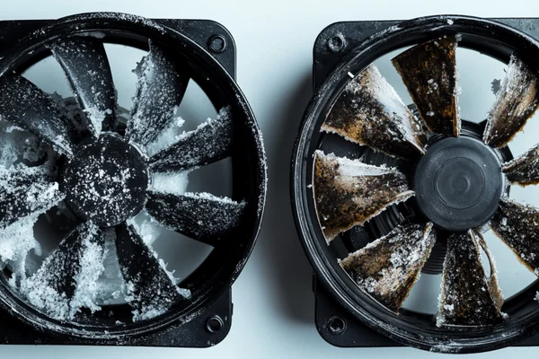 Two DC axial fans, one clean and new, the other showing heavy corrosion and UV-faded plastic after outdoor use