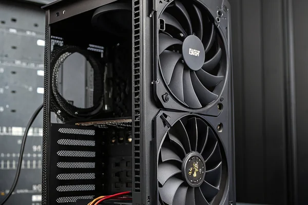 A 140mm case fan being mounted onto a mid-tower PC case front intake panel, with screw holes visible on the black steel frame