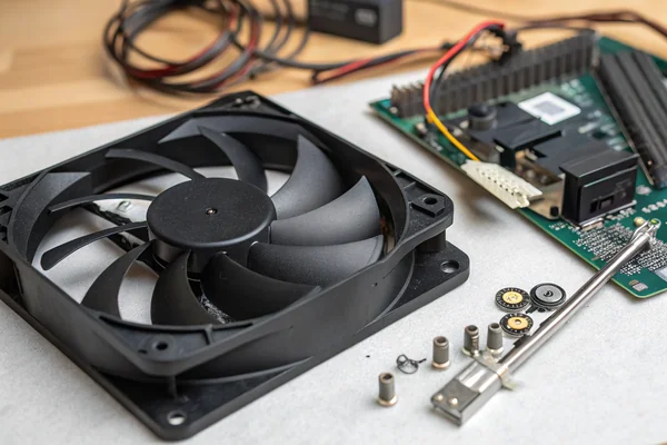 A disassembled 120mm PC cooling fan lying flat on a workbench, with the impeller blades, hub, and motor mounting frame visible in detail showing the blade pitch and frame design