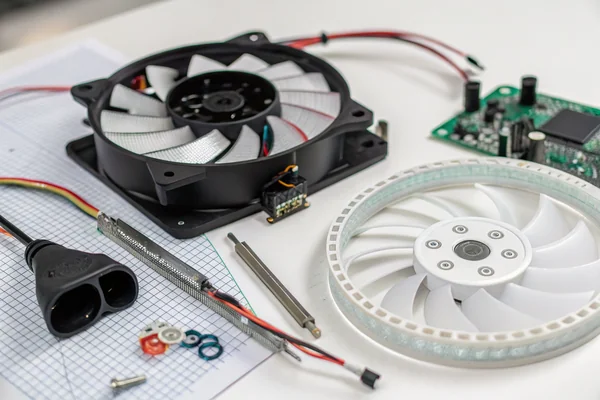 A disassembled 120mm RGB case fan laid flat on a workbench, showing the separated LED ring PCB, translucent diffuser frame, and motor hub with four blades detached