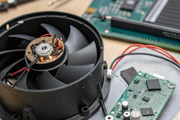 A disassembled black DC axial fan showing its brushless motor and driver circuit board