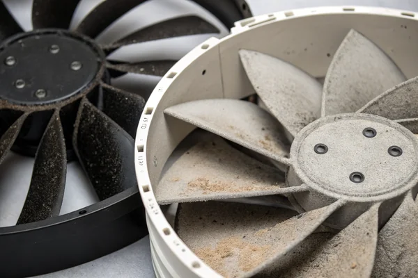 Close-up of a clean DC axial fan blade compared to a dust-caked fan blade