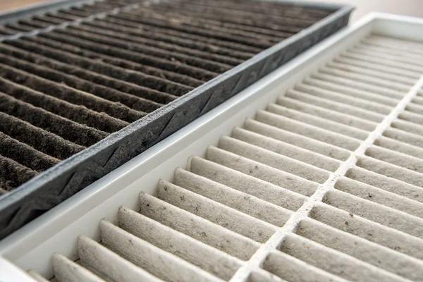 Close-up of a HEPA filter loaded with captured particulate next to a clean replacement filter