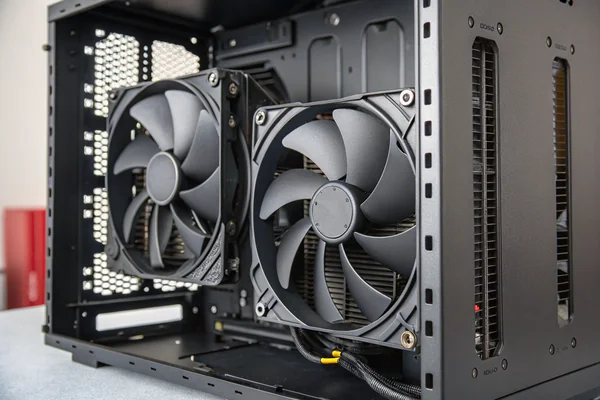 Close-up of two PC case fans installed in a steel case interior, one 120mm on the rear exhaust panel and one 140mm on the front intake bracket, both with black frames and semi-transparent blades