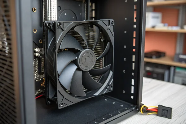 DC axial fan mounted in a PC case intake position with anti-vibration rubber corners visible against a black metal panel