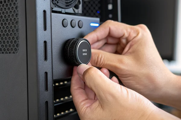 Person's hand adjusting a fan speed control knob on a desktop fan controller panel mounted in a PC case front bay