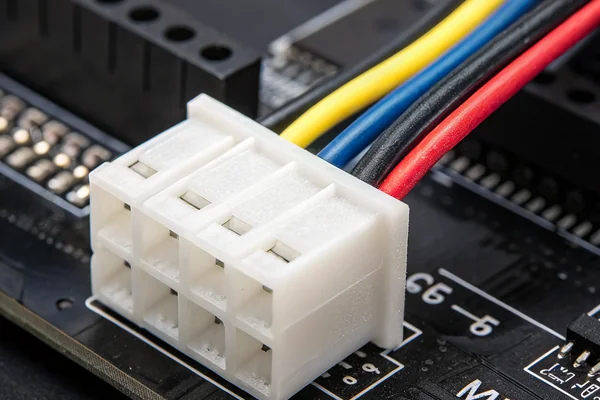Four-pin PWM PC case fan connector held against a black motherboard header, showing white plastic housing and color-coded wire leads
