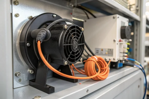 High-pressure DC blower with black plastic scroll housing mounted inside a medical device panel, with orange wiring harness routed alongside the inlet duct