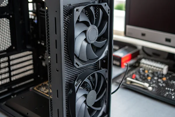 Close-up of a black 120mm PC case fan installed in an open mid-tower computer case, PWM cable routed neatly to a nearby motherboard header