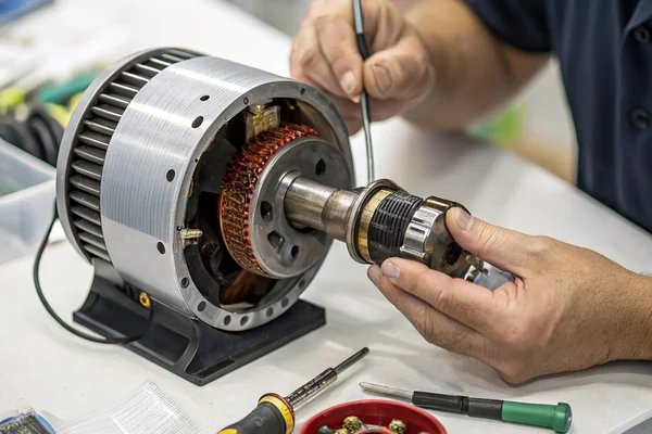 Technician inspecting the motor and bearing assembly of a disassembled DC high-speed vortex blower fan on a test bench