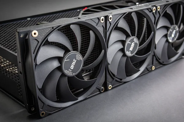 Three 120mm black PC case fans mounted in a row on a mesh front panel, showing intake arrow stickers and their orientation relative to the case interior