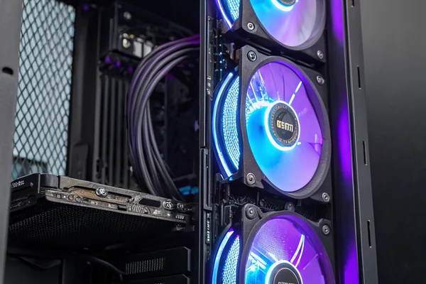 Three RGB case fans installed in a full-tower PC case, illuminated in blue and purple, with visible cable routing behind the motherboard tray