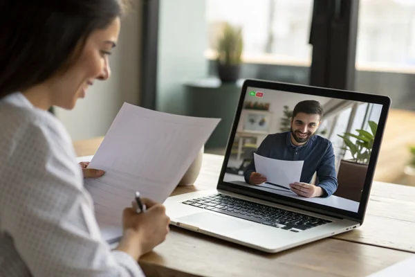 Two people on a video call reviewing a supplier questionnaire document on a laptop screen in an office setting