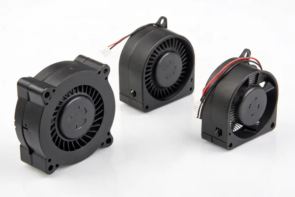 Three DC brushless blower fans in different size designations laid out side by side on a workbench for size comparison
