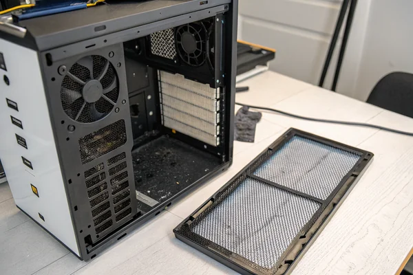 Close-up of case fan filters removed and set aside next to a PC case front intake panel, dust visibly trapped in the filter mesh