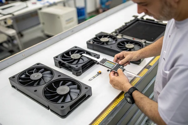 Technician comparing multiple fan samples side by side on an inspection table, checking for consistency across units