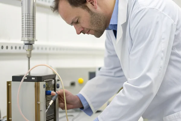 Engineer in a clean lab environment adjusting a small blower connected to a fuel cell test stack on a bench