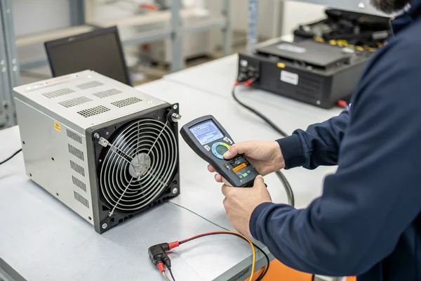 Engineer holding a handheld temperature probe near a fan-cooled enclosure to validate measured cooling performance